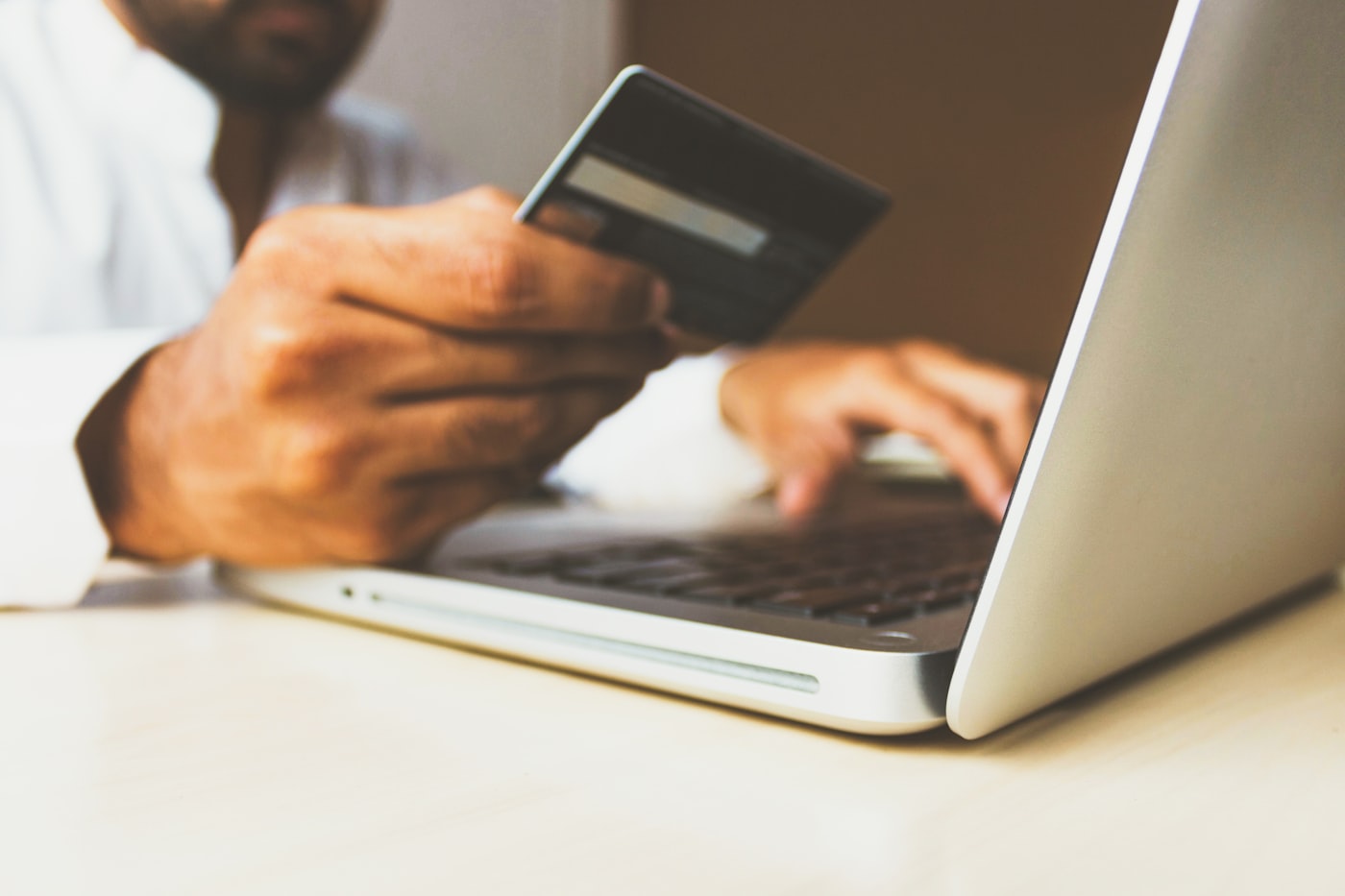 Hands holding a credit card while shopping online on a laptop